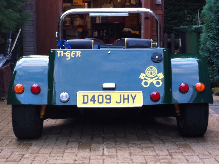 Pistonheads - This image captures an old-style, blue Mini Cooper, parked on a bricked sidewalk. The car is known for its racing heritage, and this particular model has a distinctive logo of a cougar on the side. It's facing upwards, which suggests it might have been recently parked. The background is a bit blurred, emphasizing the car as the main subject of the photo. The lighting appears to be natural, and the surroundings suggest a calm, quiet street.