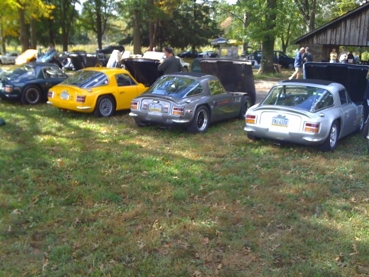 TVR classic pic in california - Page 1 - TVR in USA - PistonHeads - The image features a collection of four vintage cars displayed on grass. These small vehicles exhibit a variety of colors: yellow, silver, and black. Some cars have movable parts missing, suggesting they may not be fully functional. The cars are parked within a regular parking lot, with trees visible in the background. There are also several people present in the background, indicating that this may be a car show or similar public event.