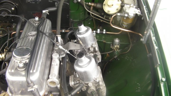 A close up of a motorcycle parked in a garage - Pistonheads - The image shows a close-up view of an engine compartment, focusing on the engine block and mechanical components. Several different engine parts are visible, including a header with a muffler, wiring connected to the parts, and metallic cylindrical components that appear to be gears or parts of the engine. The overall appearance is mechanical and industrial, suggesting a complex piece of machinery.