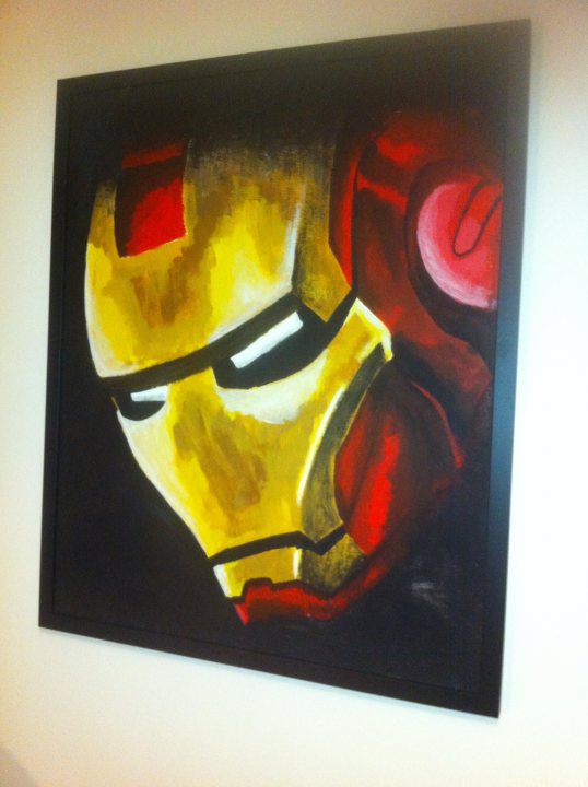 Art on your walls... - Page 10 - Homes, Gardens and DIY - PistonHeads - The image features a painting of Iron Man's helmet on a wall. The helmet, painted in a realistic style, is depicted in a blend of yellow and red, creating a striking contrast against the black background. The artist has skillfully used different shades of yellow and red to highlight the contours and intricate details of the Iron Man design. The painting is framed in black, complementing the color scheme of the artwork. The vibrant colors and the detailed depiction of the helmet make this a striking piece of wall art.