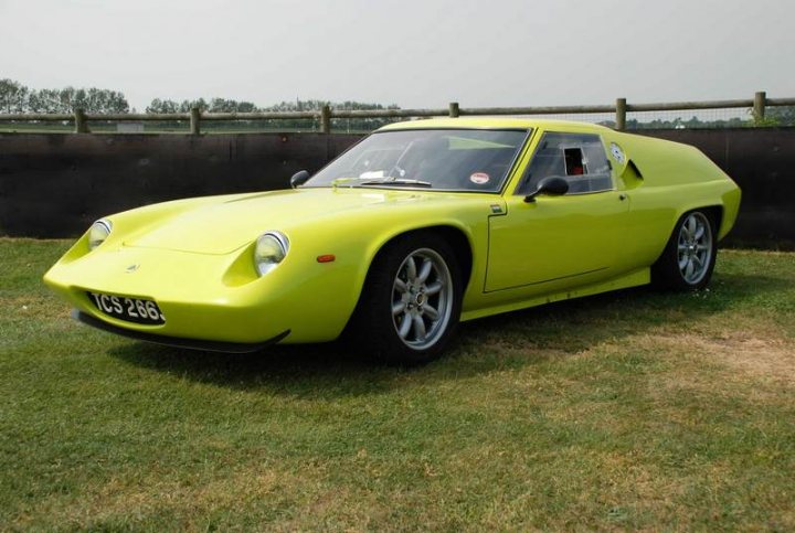 Supercar Sunday Pistonheads - The image depicts a vibrant, bright yellow sports car parked on what seems to be a grassy area. The car has a sleek and low-profile design, characterized by large, round headlights. It features two doors and a long hood, giving it a classic sports car look. The car is parked in a wide, open space, possibly at a car show or a racetrack, given the direction of the fence in the background, which suggests a controlled environment dedicated to such events.