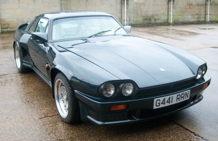 Pistonheads Etype Xjs Imho - The image shows a well-maintained car standing on a wet concrete lot. The car has a striking color combination with a green body and a white roof, giving it a sleek and modern appearance. It features two doors on the side and an open boot. The design suggests it might be a classic or sports car. The license plate, visible on the back, reads "G44 RNR". The wet surface reflects the car's elegant lines and emphasizes its elegance. The background is modest, with a simple stone construction adding an urban touch to the scene.