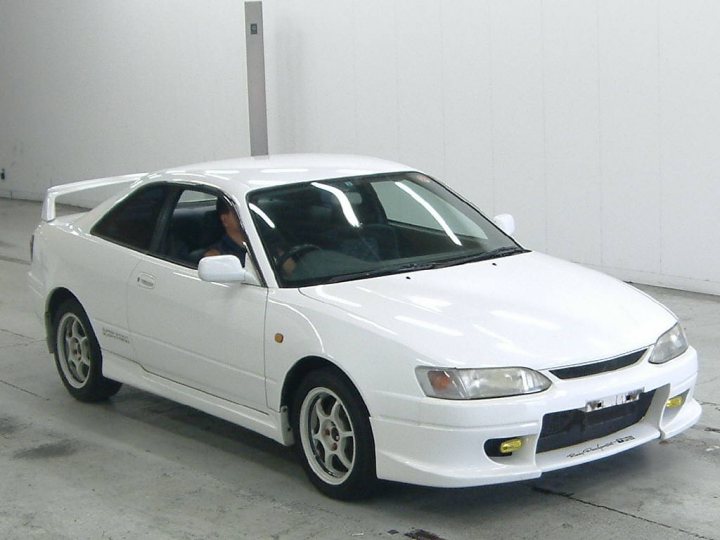 Thinking of getting a import?  - Page 1 - Jap Chat - PistonHeads - The image shows a white car positioned indoors against a white wall. The car's design is consistent with Japanese coupe cars of the 1990s, characterized by a pre-facelift body style known as the "Z31" generation. The vehicle is seen from a front three-quarter perspective, highlighting its front end, headlights, and the unique front bumper design typical of this era. The interior of the car is not visible due to the direction of entry depicted by the open passenger door.