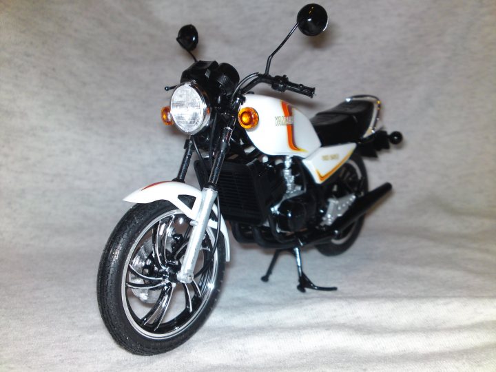 Tamiya Pistonheads Yamaha Rdlc - The image shows a model of a white and black motorcycle with sidecars, positioned against a white background. The motorcycle has prominent headlights and features two black wheels with silver spokes. Gas and sidecar locks are visible, and it appears to be a small, detailed collectible item given its realistic and miniature appearance.