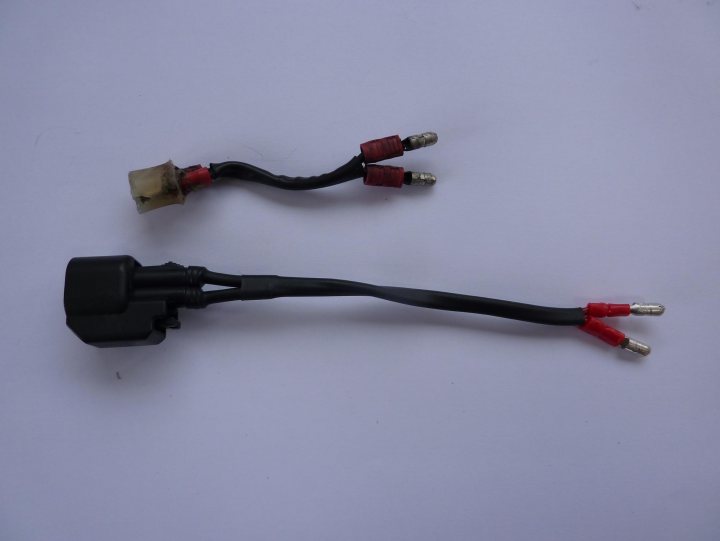 A pair of scissors sitting on top of a table - Pistonheads - This image shows two electronic connectors with their red wires intact, lying on a white surface. There appears to be some bare wire exposed at the ends of the connectors, with no other cables or components attached. The wires are neat and the connectors are compact, suggesting they could be from a small electronic device or wiring accessory. The background is plain and doesn't distract from the items. No other objects are visible, and the focus is entirely on the two connectors.