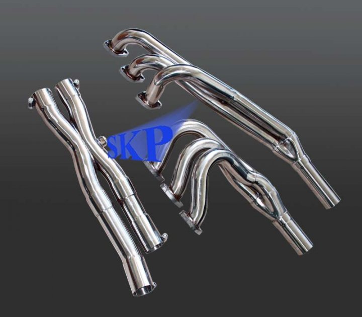 Pistonheads - The image features a subset of what appears to be a set of engine exhaust pipes. They are shiny, chrome-plated, and shaped in an aesthetically pleasing circular pattern. The design suggests a premium or high-performance vehicle, given the embossed 'SKP' text on one of the pipes, which could indicate a specific model or branding. The background is a uniform dark gray, providing a strong contrast to the metallic pipes and allowing them to be the focal point of the image. There is a slight reflection on the left side of the image, suggesting a source of light illuminating the pipes and possibly the photographer.