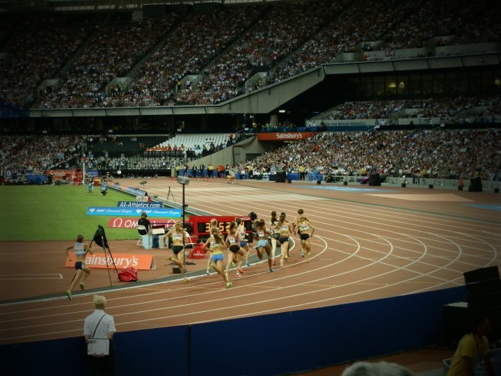 Anniversary Games Athlectics. Anyone Watching? - Page 1 - Sports - PistonHeads - The image captures the intensity of a running competition in a large stadium. A group of athletes, possibly women, are in the midst of the race, their expressions intent as they push themselves forward. The stadium seats are filled with spectators, their focus on the unfolding race. In the foreground, a photographer is positioned, capturing the action as the runners outrace each other. On the sidelines, red and blue sports equipment can be seen, adding to the overall sports theme of the event. The image is a dynamic snapshot of athletic competition.