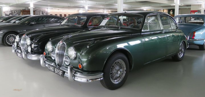 Pistonheads - The image showcases a collection of vintage cars displayed indoors. The main focus is a green antique car, which appears to be the oldest and largest vehicle among them. This car stands out due to its classic design and vibrant color. Surrounding it are several other vintage models in various colors like blue, red, and black, each exhibiting distinct characteristics of their respective eras. The cars are neatly arranged within what seems to be a spacious garage or showroom, suggesting a place dedicated to the preservation and display of these classic vehicles.