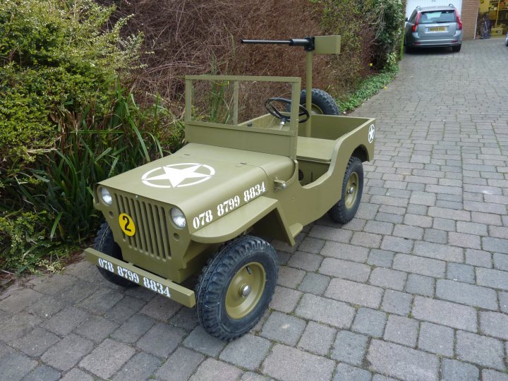 Interim Tuesday Curry Pistonheads - The image features a small, off-road vehicle, specifically a replica of a World War II jeep. It has a green body with a khaki hood, and the number 178 5814 is visible on the side. The vehicle is parked on a gravel path, with a Yellowstone National Park license plate suggesting it might be part of a themed attraction or collection. The background includes shrubbery and a parked car, indicating a suburban setting.