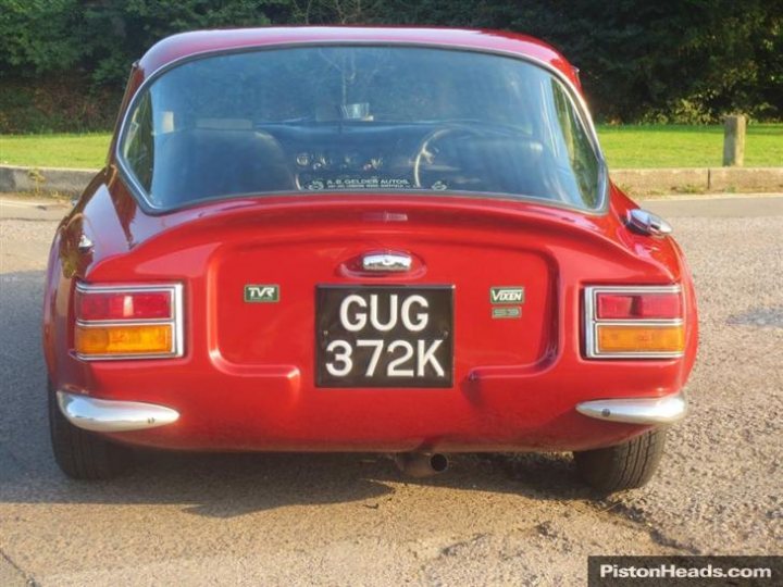 Early TVR Pictures - Page 44 - Classics - PistonHeads - The image shows a close-up of the rear end of a classic red two-door coupe. The tailgate is adorned with a black and white license plate that reads "GU872K," indicating the vehicle has a U.K. registration. The older design and the partially visible wing suggest a vehicle from a previous generation. The car is parked in a driveway or street, and there's a hint of the grass beyond the immediate setting. The photo emphasizes the classic design and the registration detail of the model.