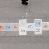 Youtuber chalks a hopscotch game on the sidewalk and records those who stop to play.